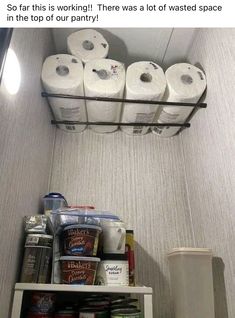 a shelf with several rolls of toilet paper on it and some cans in the bottom