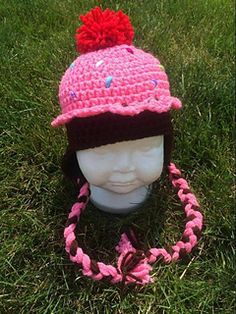 a crocheted hat with a red pom - pom on it sitting in the grass