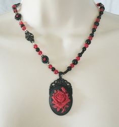 "Red Rose Necklace This beautiful necklace has red glass beads, black glass beads, seed beads, black metal connectors with rhinestones, black metal chain and a black metal pendant with resin rose. 20\" long. Lobster clasp." Gothic Beaded Necklace For Gift, Gothic Black Beads Necklace For Jewelry Making, Gothic Beaded Jewelry Gift, Gothic Beaded Jewelry For Gift, Gothic Black Bead Necklace For Gift, Gothic Black Necklaces With Round Beads, Gothic Black Beads Necklace For Gift, Handmade Gothic Beaded Necklaces With Round Beads, Handmade Red Victorian Necklace