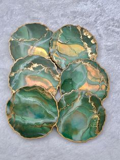 four green and gold leaf shaped dishes sitting on top of a white surface with snow