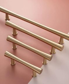 four brass handles on a pink and white wall