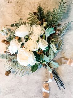 a bridal bouquet with white flowers and greenery on a marble surface, ready to be used as a wedding centerpiece