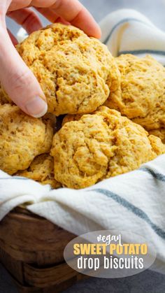 a person picking up some sweet potato drop biscuits from a wooden bowl on a table