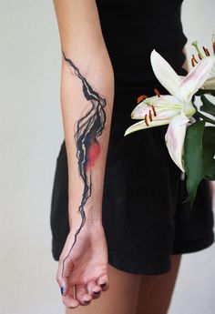 a woman with a tattoo on her arm holding a bouquet of lilies in her hand