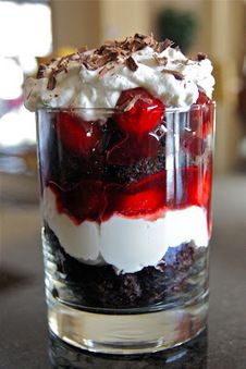 a dessert in a glass with whipped cream and strawberries