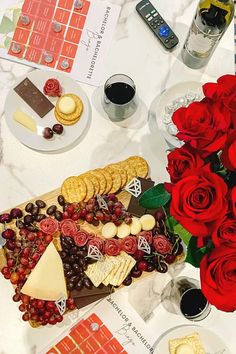 a table topped with red roses, cheese and crackers