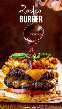 A rodeo burger with everything but the top bun is on a piece of parchment paper on a wooden countertop. A spoon above the burger is drizzling barbecue sauce on the burger. Bbq Sauce For Burgers, Rodeo Burger Recipe, Elevated Burger Recipes, Fancy Burgers Ideas, Burger Ideas Restaurant, Western Burgers Recipes, Smash Burger Ideas, Best Burger Recipes, Creative Burger Ideas