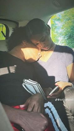 a man and woman sitting in the back seat of a car looking at their cell phones