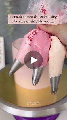 someone is decorating a cake using pink icing and two silver tip tips on top