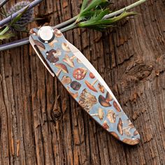 a knife sitting on top of a wooden table next to some flowers and scissors in front of it