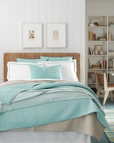 a bed in a bedroom with white walls and blue comforter on top of it