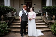 a bride and groom standing in front of a house with steps leading up to it