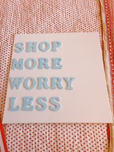 a sign that says shop more worry less on it next to a red and white table cloth