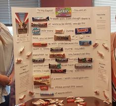 two women standing next to a poster with candy bars on it