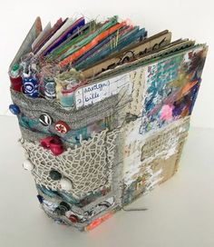 an altered book with lots of papers in it's pocket on a white surface