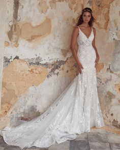 a woman standing in front of a wall wearing a wedding dress