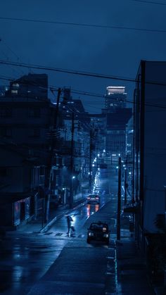 a city street at night with cars and people walking on the sidewalk in the rain