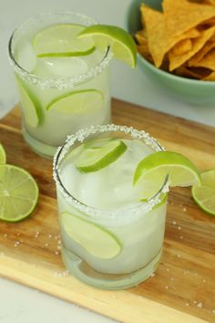 two margaritas on a cutting board with chips