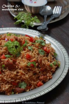 a plate full of rice with meat and cilantro on it next to silverware