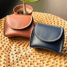 two leather wallets sitting on top of a wicker table next to a potted plant