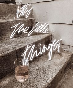 a glass of wine sitting on top of some steps with the words life is the little things above it