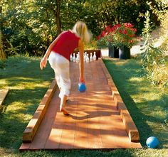 an image of a person playing with balls on a wooden walkway in the grass and trees