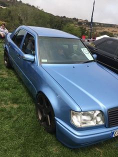 a blue car parked in the grass next to other cars