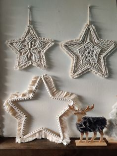 three ornaments are hanging on the wall next to a stuffed animal and other items in front of them