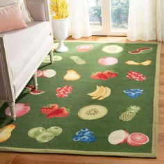 a green area rug with fruits and vegetables on it in front of a couch, window