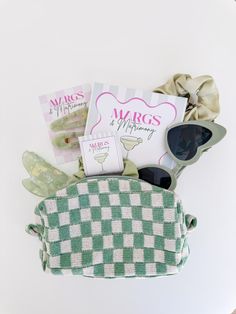 a green and white checkered purse with sunglasses on it, next to some other items