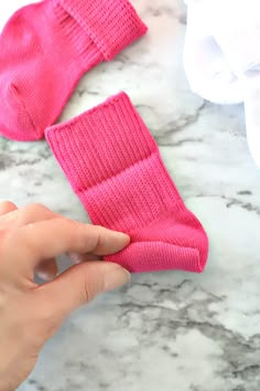 someone is holding the top of a pair of pink mittens on a marble surface