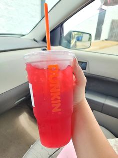 a person holding up a drink in the back seat of a car on a sunny day