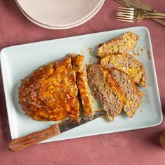 meatloaf and bread on a blue plate next to a knife, fork and spoon