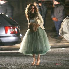 a woman in a green dress is walking down the street