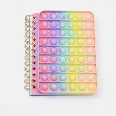 a rainbow colored notebook with lots of circles on the cover and spiral binder attached to it