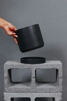 a hand is reaching for a cup on top of a cinder block structure that's made out of concrete blocks