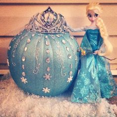 a doll is standing next to a pumpkin shaped like a princess's purse and crown