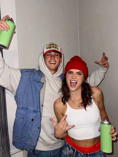 two people dressed in costumes posing for the camera with one holding a green can and another wearing a red beanie