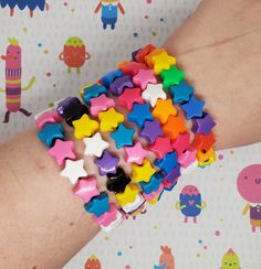 a person's arm is covered with colorful stars and other small pieces of plastic