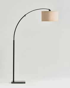 a black floor lamp with a beige shade on it's side and a white wall in the background