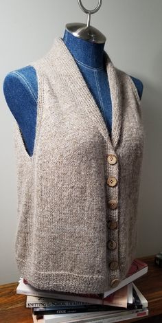 a sweater vest with buttons on it sitting on top of books