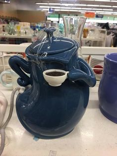 a blue teapot with a cup in it sitting on a counter