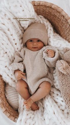 a baby in a knitted sweater and hat laying on a blanket with teddy bears