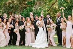 a large group of people in formal wear posing for the camera with their hands up