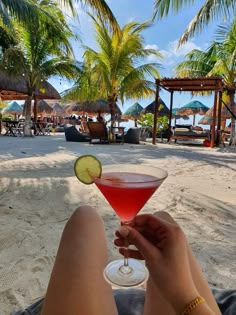 a person sitting on the beach holding a cocktail