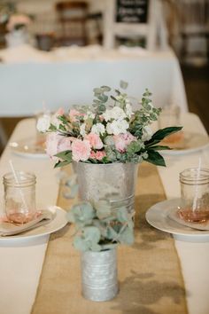 a vase with flowers and greenery is sitting on a table at a wedding reception