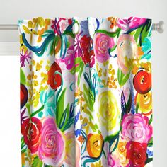 a colorful curtain with flowers on it hanging from a window sill in front of a white wall