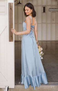 a woman in a blue dress is standing by the door and looking at her bouquet