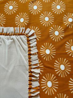 an orange and white bed spread with ruffles on the bottom, and sunbursted background