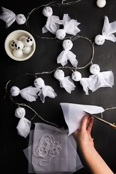 someone is cutting out paper with scissors and some decorations on the table behind them that are made to look like ghost heads